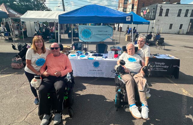 Two ALS patients with their caregivers at a Let Hope Grow awareness event, showcasing support and advocacy for ALS families.