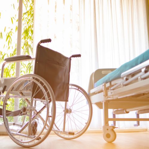 A wheelchair next to a hospital bed in a bright room, representing accessible medical equipment for ALS patients.