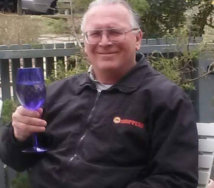 Ed Belair smiling and holding a blue glass in Manassas VA before ALS progression