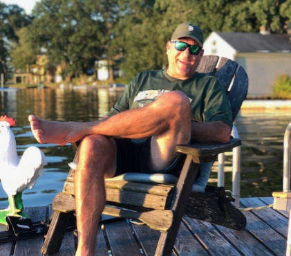 ALS patient Mike Foster sitting on a lakeside dock in California, smiling in the sun