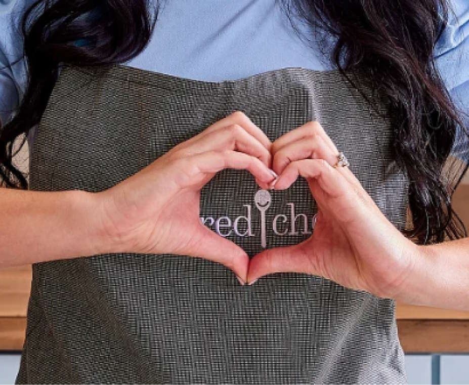 Pampered Chef apron with hands forming a heart, symbolizing support for ALS families during Let Hope Grow’s virtual fundraiser.