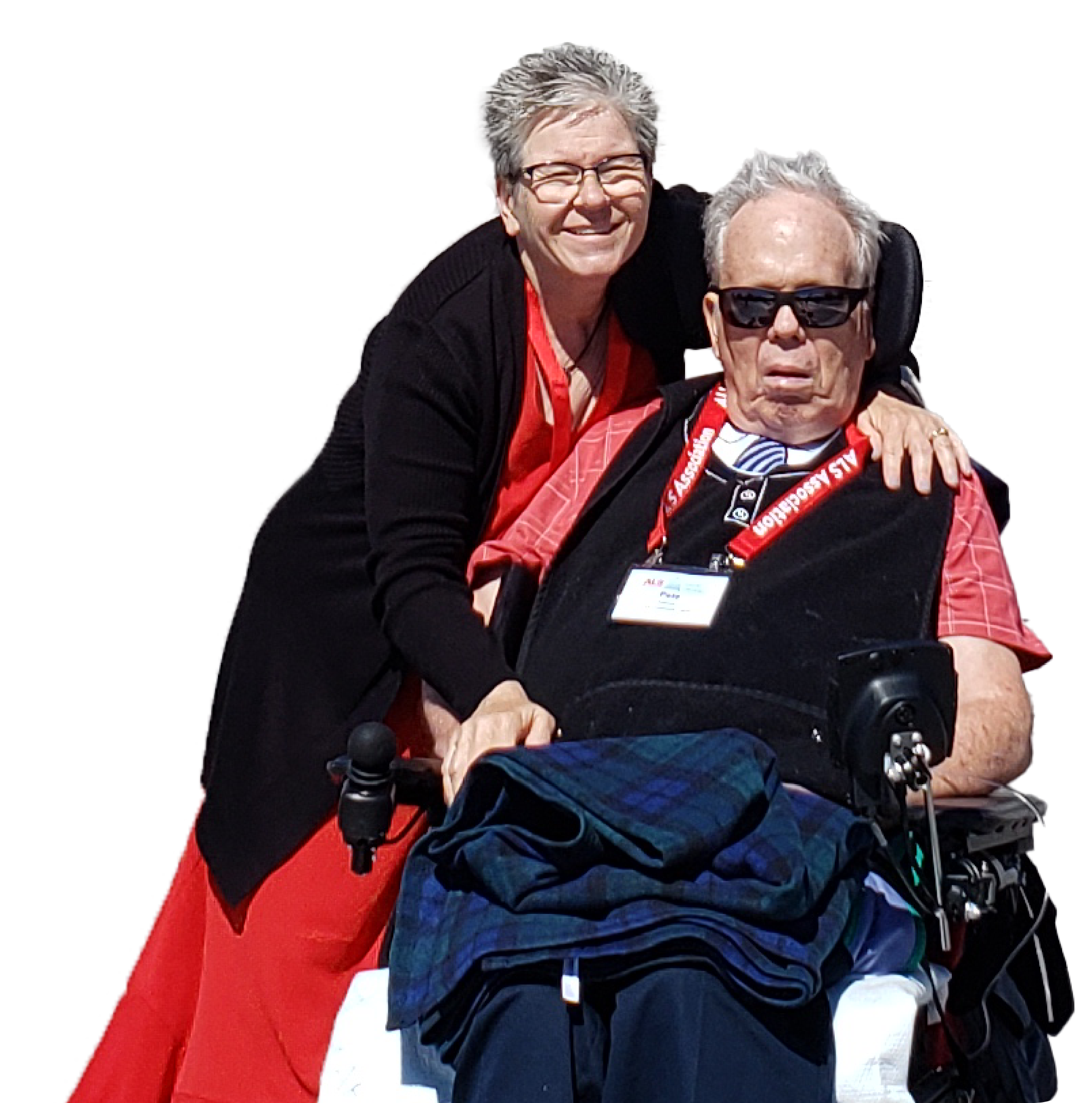 Person with ALS sitting in wheelchair with his caregiver with her arm around him.